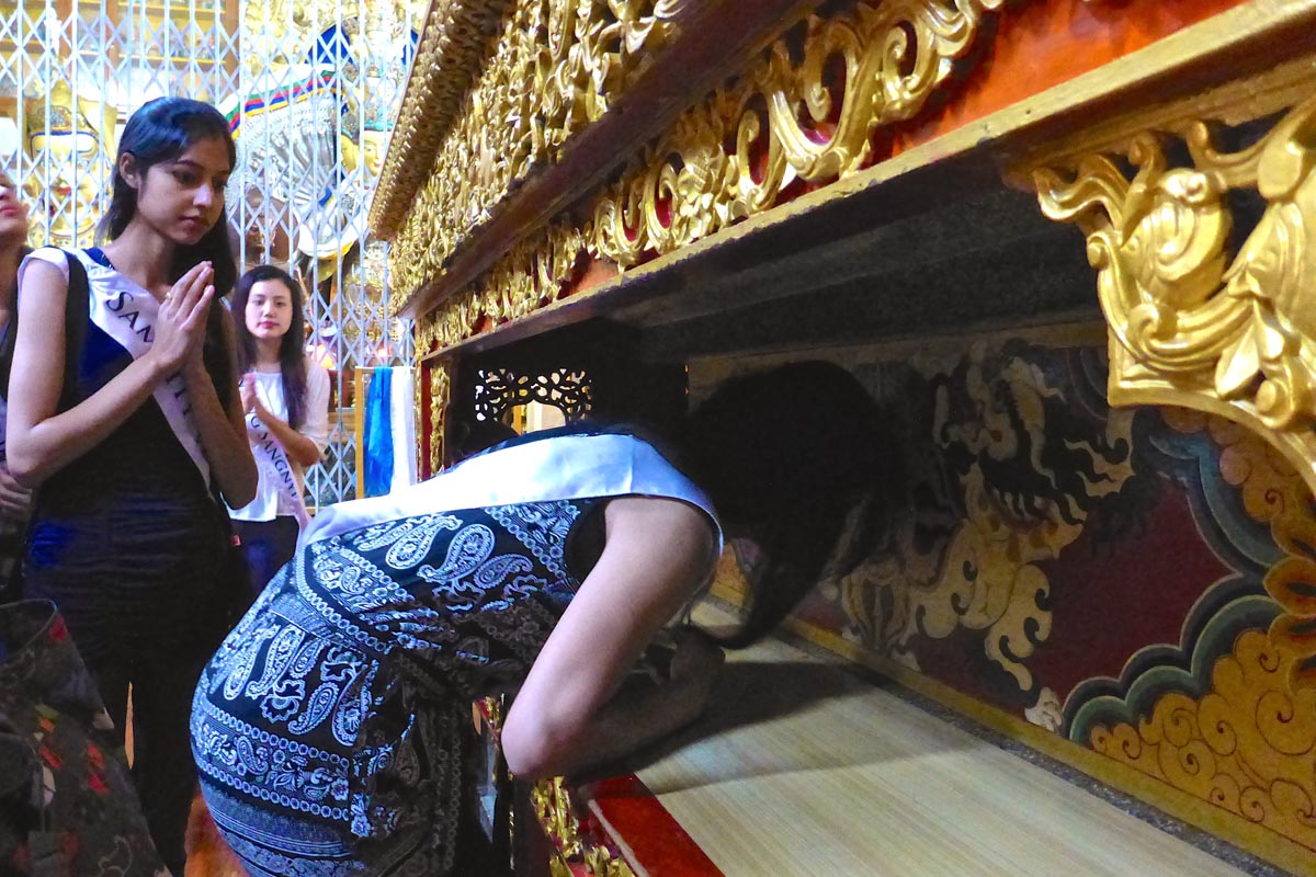 Contestant Swattee Thakur placing her forehead on His Holiness the Dalai Lama's throne at the Temple.